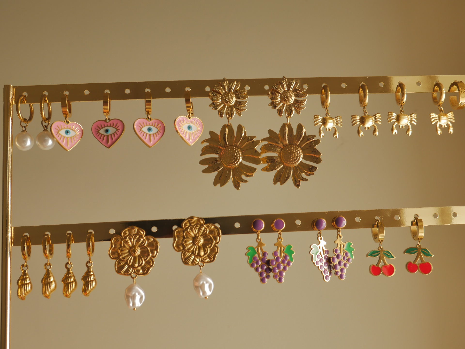 Collection of earrings on a gold rack against a beige background