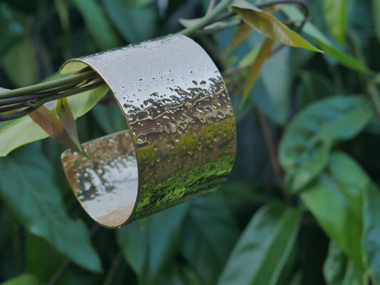 Metallic cuff on a branch with green leaves in the background