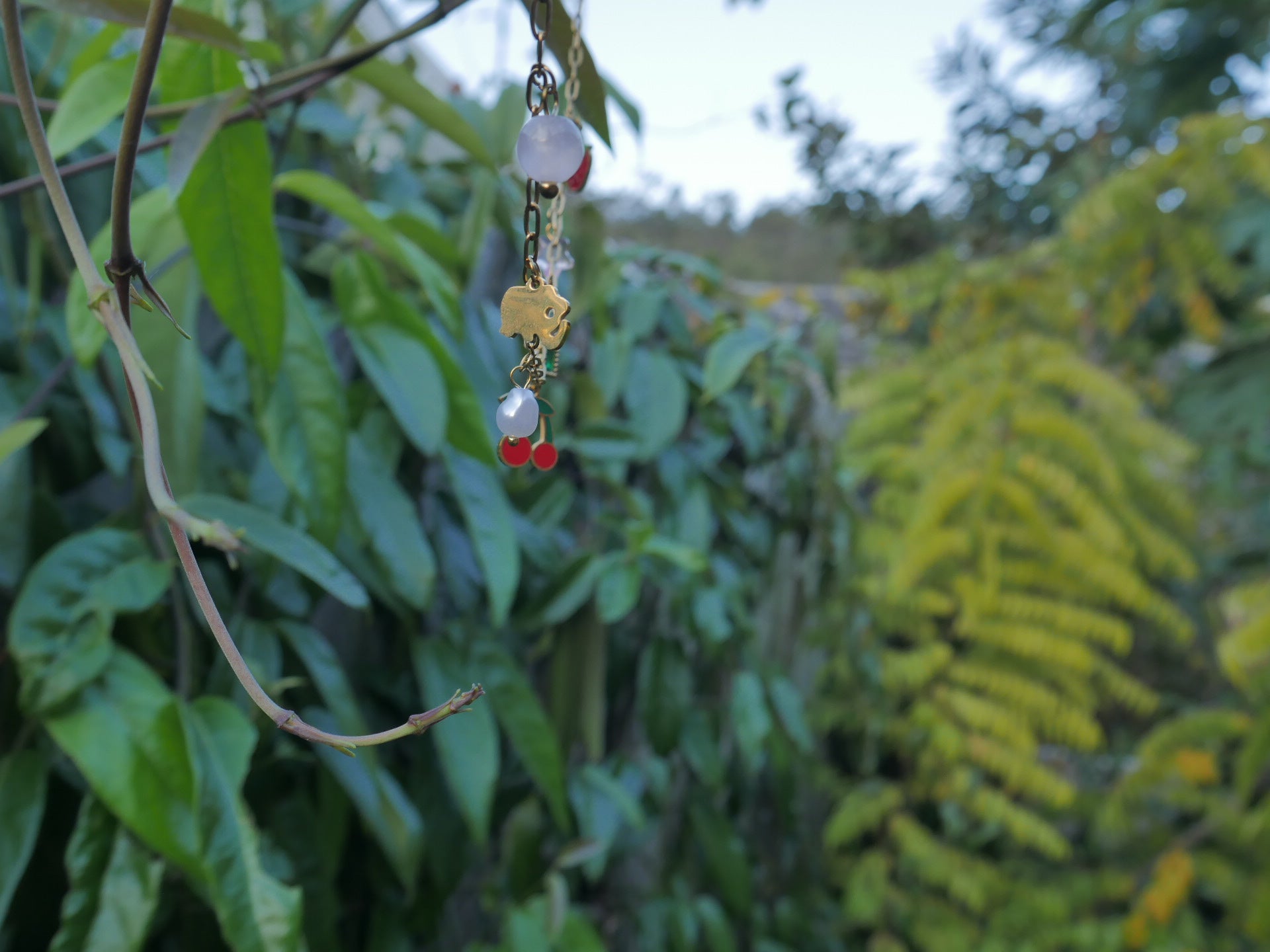 Necklace with beads hanging from a branch against a green leafy background