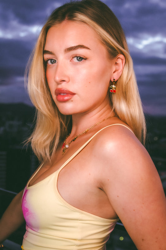 Woman with blonde hair and a yellow top against a dark sky background