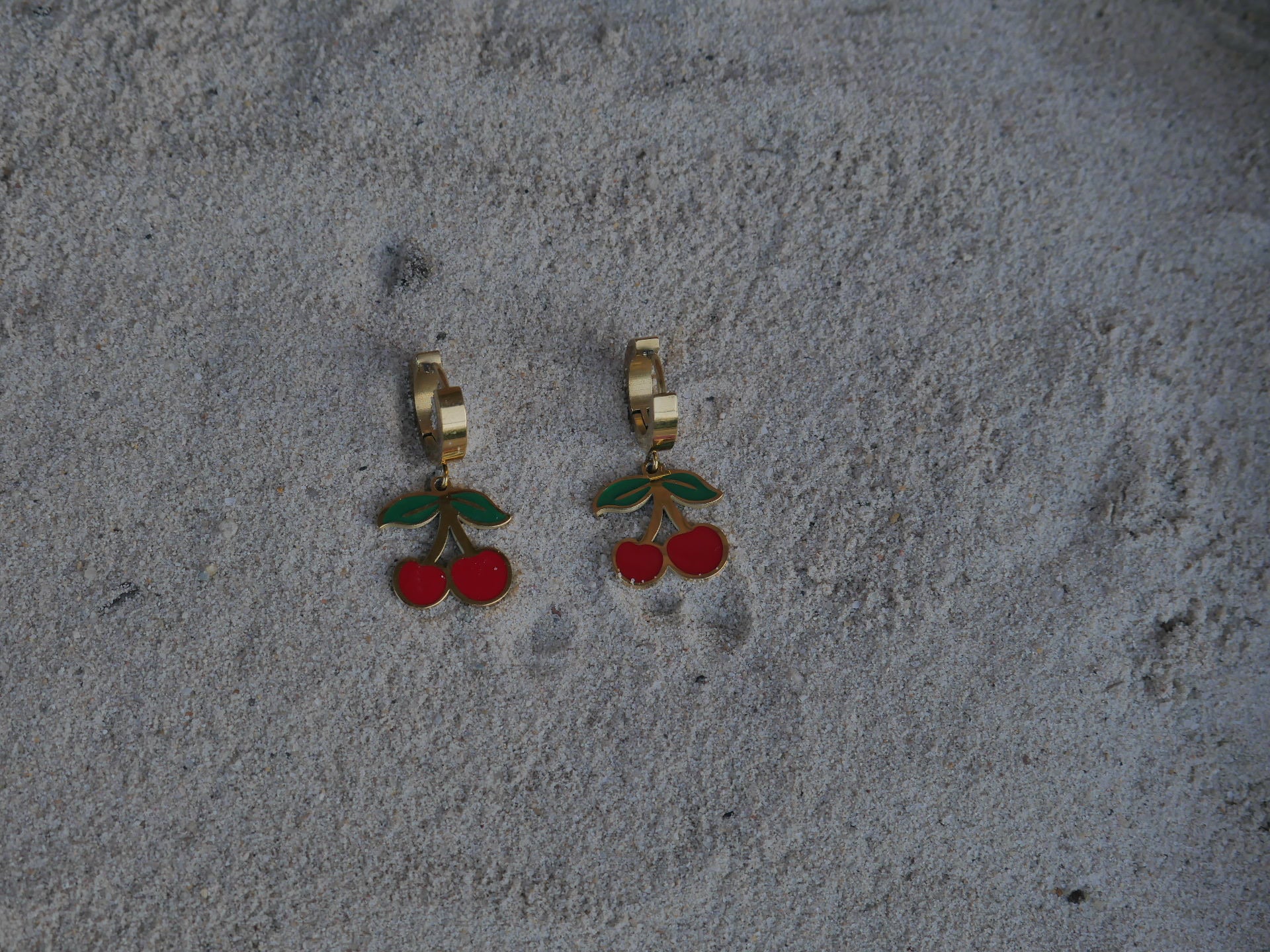 Cherry-themed earrings on a textured gray surface