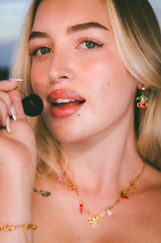 Close-up of a person wearing a gold necklace with red accents.