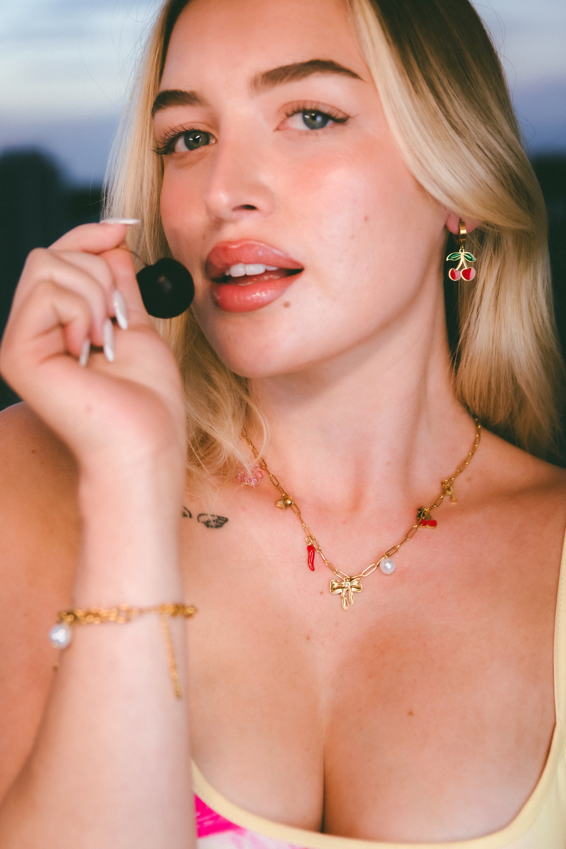 Woman holding a cherry with a blurred natural background