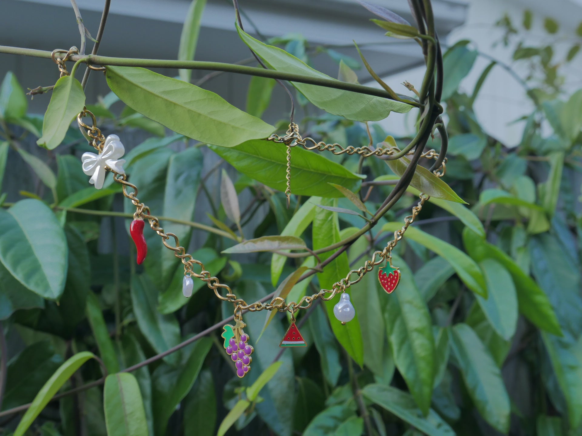 Necklace with colorful charms on a branch with green leaves