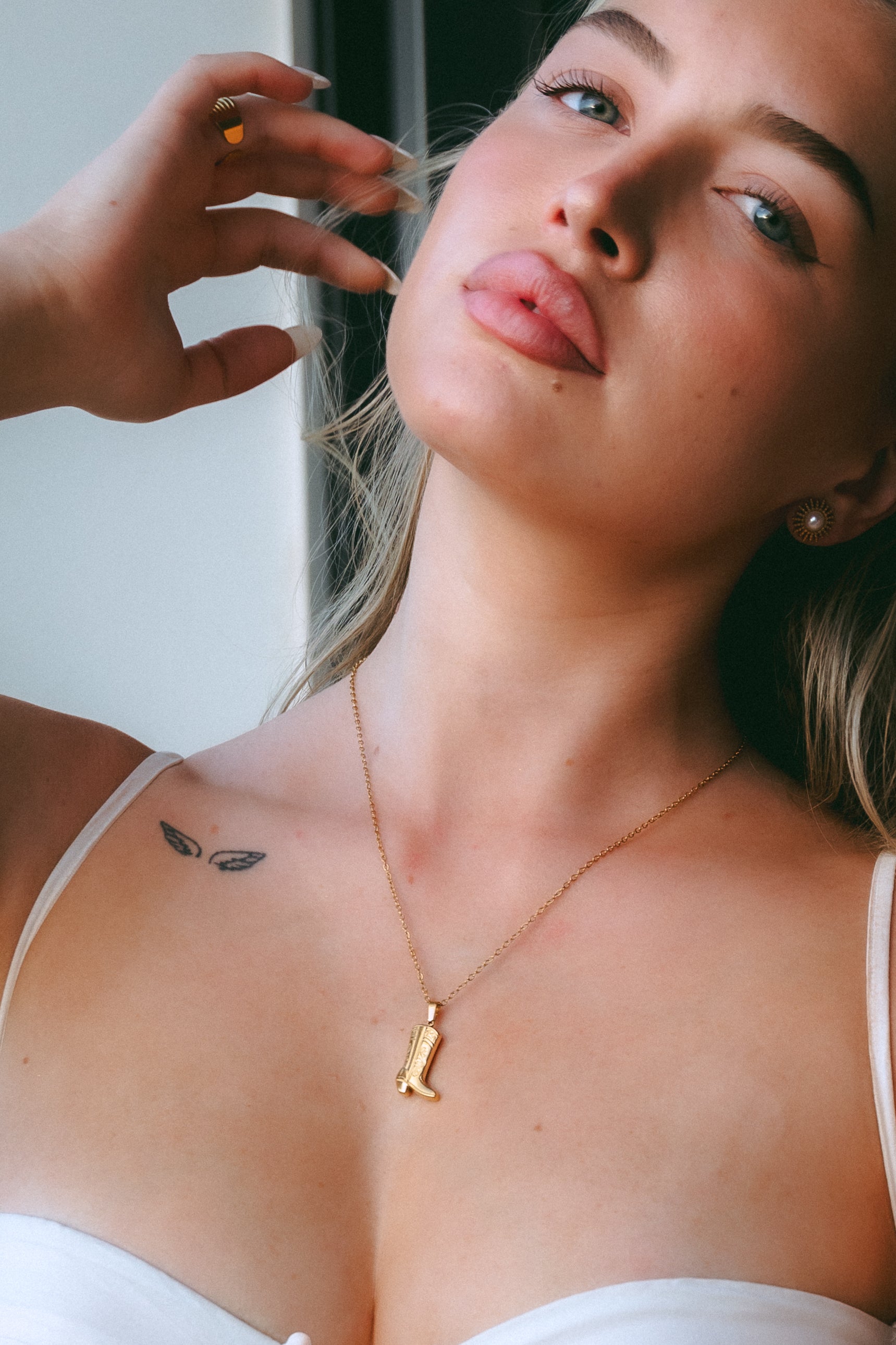 Woman wearing a gold necklace with a pendant, close-up of her neck and chest.