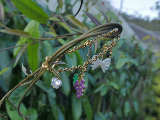 Gold bracelet with charms on a green leafy background