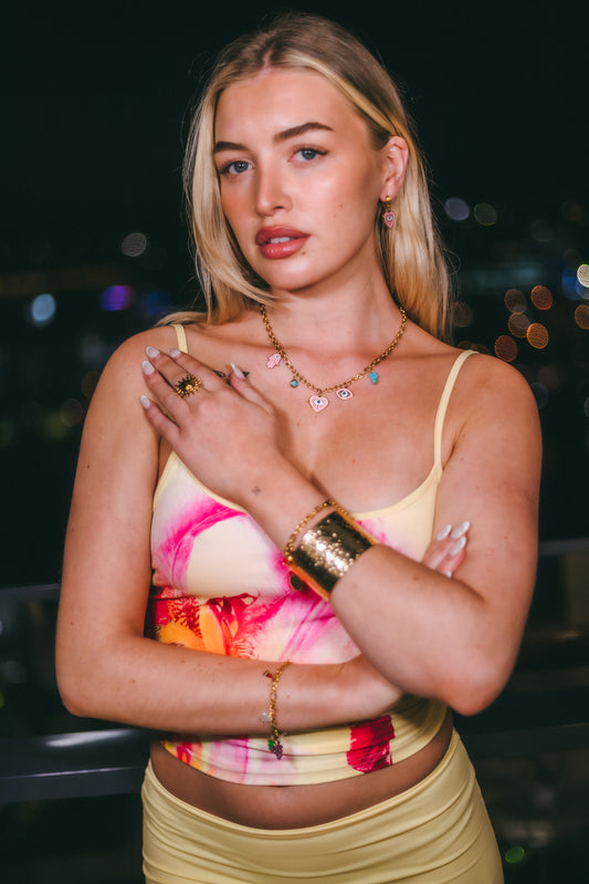 Woman wearing a colorful top and skirt with jewelry against a blurred background