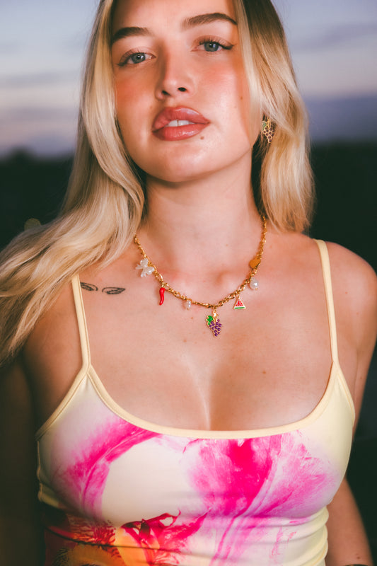 Woman wearing a colorful tank top and necklace with a blurred natural background